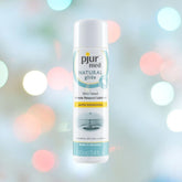 A 100ml bottle of Pjur Med Natural Glide Personal Lubricant by Pjur, known for its hypoallergenic and natural water-based formulation, is centered against a softly blurred background featuring colorful bokeh lights. The label emphasizes "gentle moisturizing" and its compatibility with latex condoms.